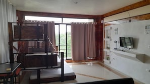 A room with a bed, a TV, a desk, and a window with curtains. - El Castillo Monte Campana (Lagunillas)