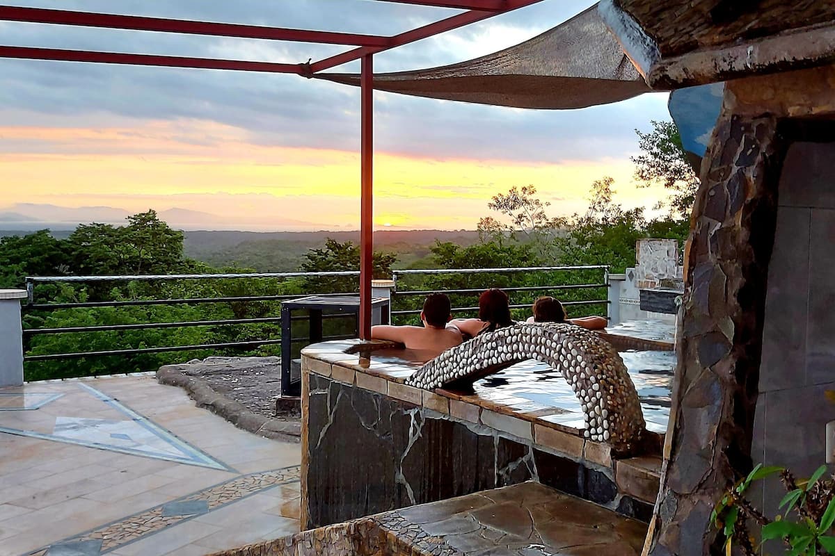 A terrace with a stone bench, a stone wall, and a view of the landscape.