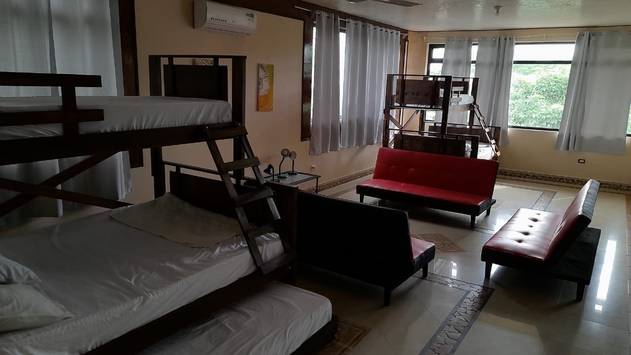 A room with bunk beds, a red sofa, and a small table.