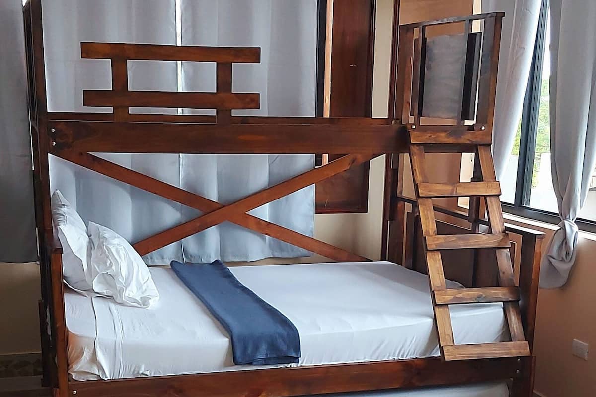 A wooden bunk bed with a ladder, a white pillow, and a blue blanket.