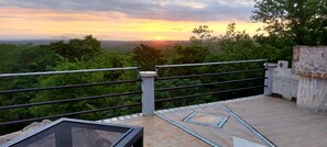 A terrace with a view of the sunset over a forested landscape. - El Castillo Monte Campana (Lagunillas)