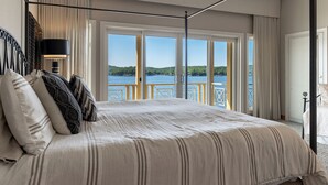 A bedroom with a large bed, a view of the sea, and a balcony with a railing. - Allie's - Amazing 8,000 SF Home with --Private Pool--hot tub-- Sleeps 26+  (Sunrise Beach)