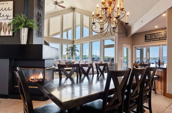 Un comedor con chimenea, una araña y vistas al exterior.