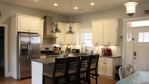 A modern kitchen with white cabinetry, stainless steel appliances, and a central island with chairs. - Beautiful waterfront home on a private cove in Lake Keowee w/ hot tub (Seneca)