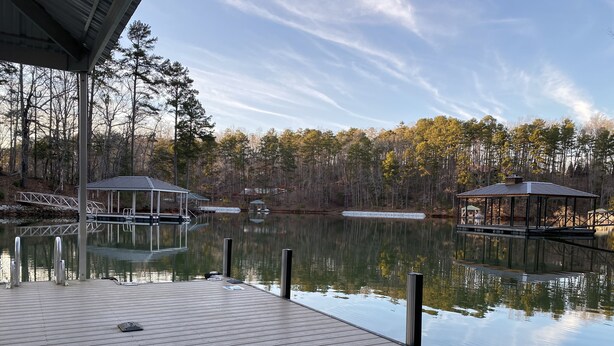 A wooden dock extending over calm water, with a gazebo and a covered area on the left and a similar structure on the right. - Beautiful waterfront home on a private cove in Lake Keowee w/ hot tub (Seneca)