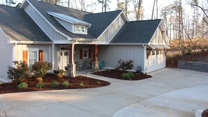 A two-story house with a front porch, a garage, and a landscaped front yard. - Beautiful waterfront home on a private cove in Lake Keowee w/ hot tub (Seneca)