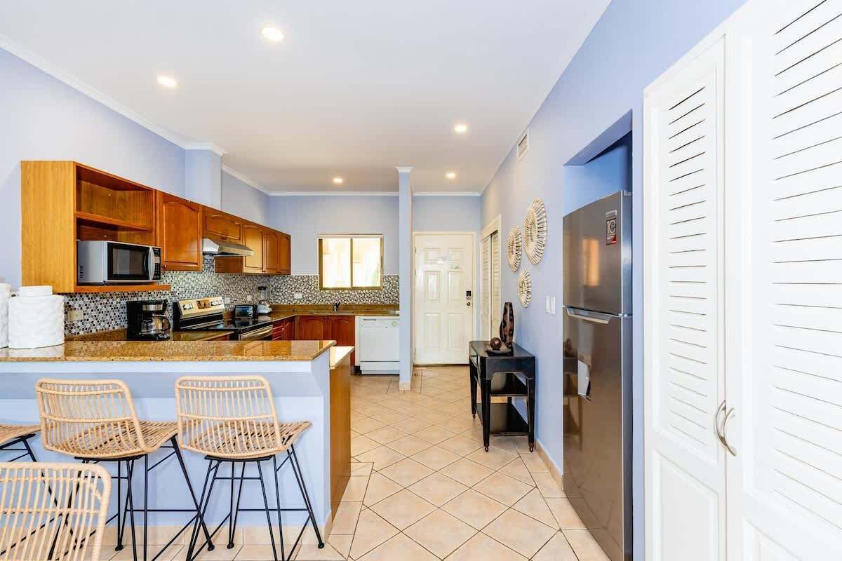 A modern kitchen with wooden cabinets, a built-in microwave, and a central island with bar stools.
