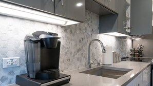 Een moderne keuken met een koffiezetapparaat, een spoelbak en een backsplash van hexagontegels.