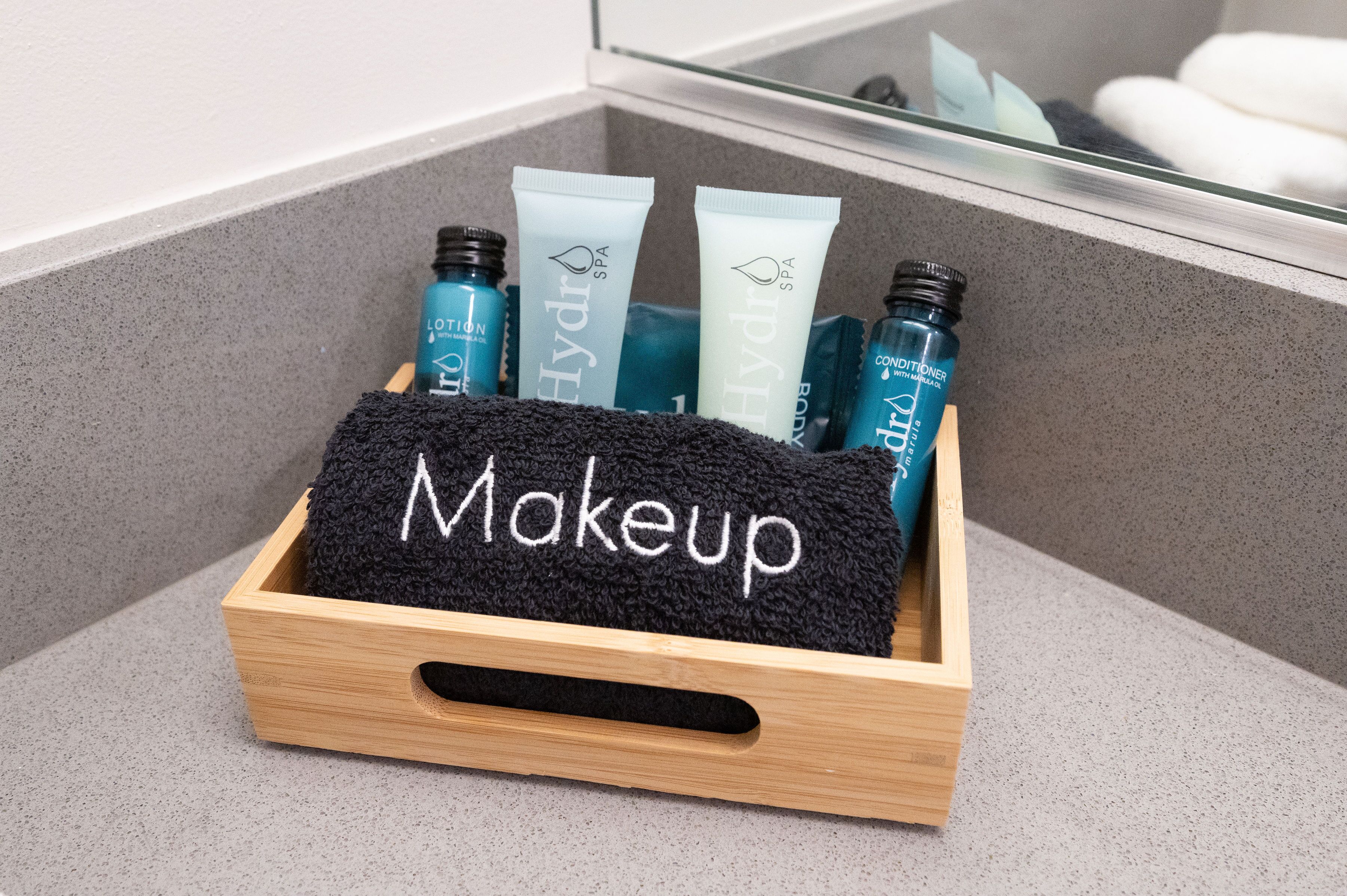 En træmakeup-organisator med et sort håndklæde mærket "Makeup", der indeholder forskellige hudplejeprodukter.