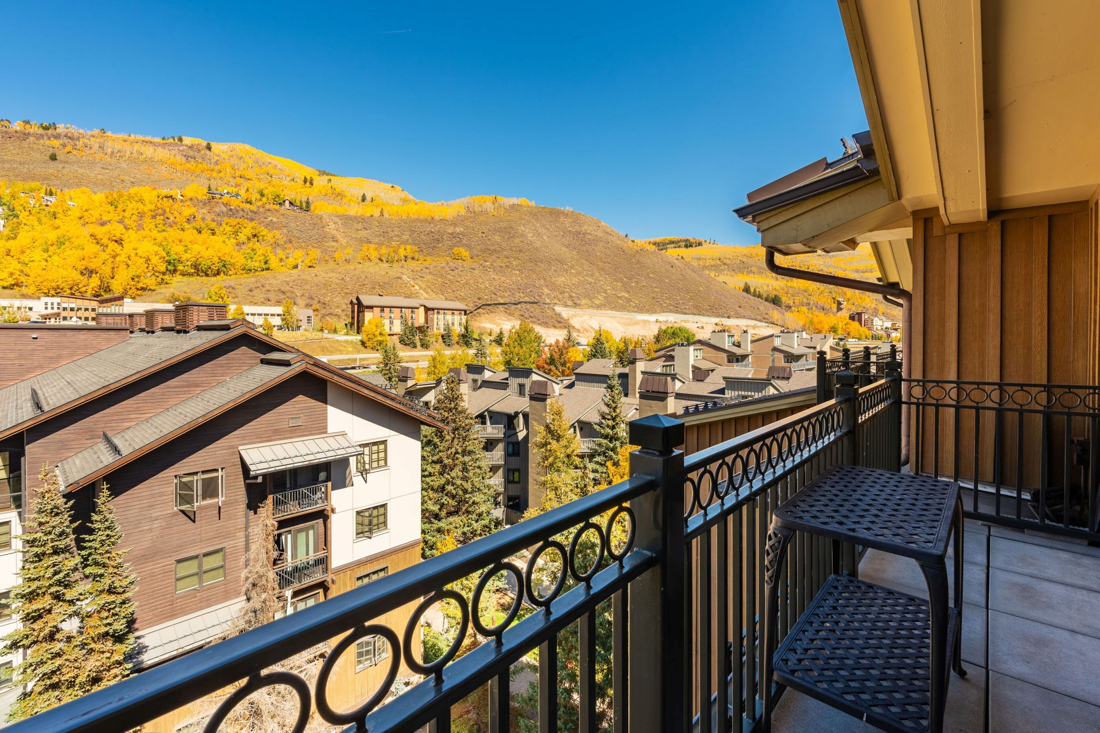 A balcony with a view of a town and a hill with autumn foliage.