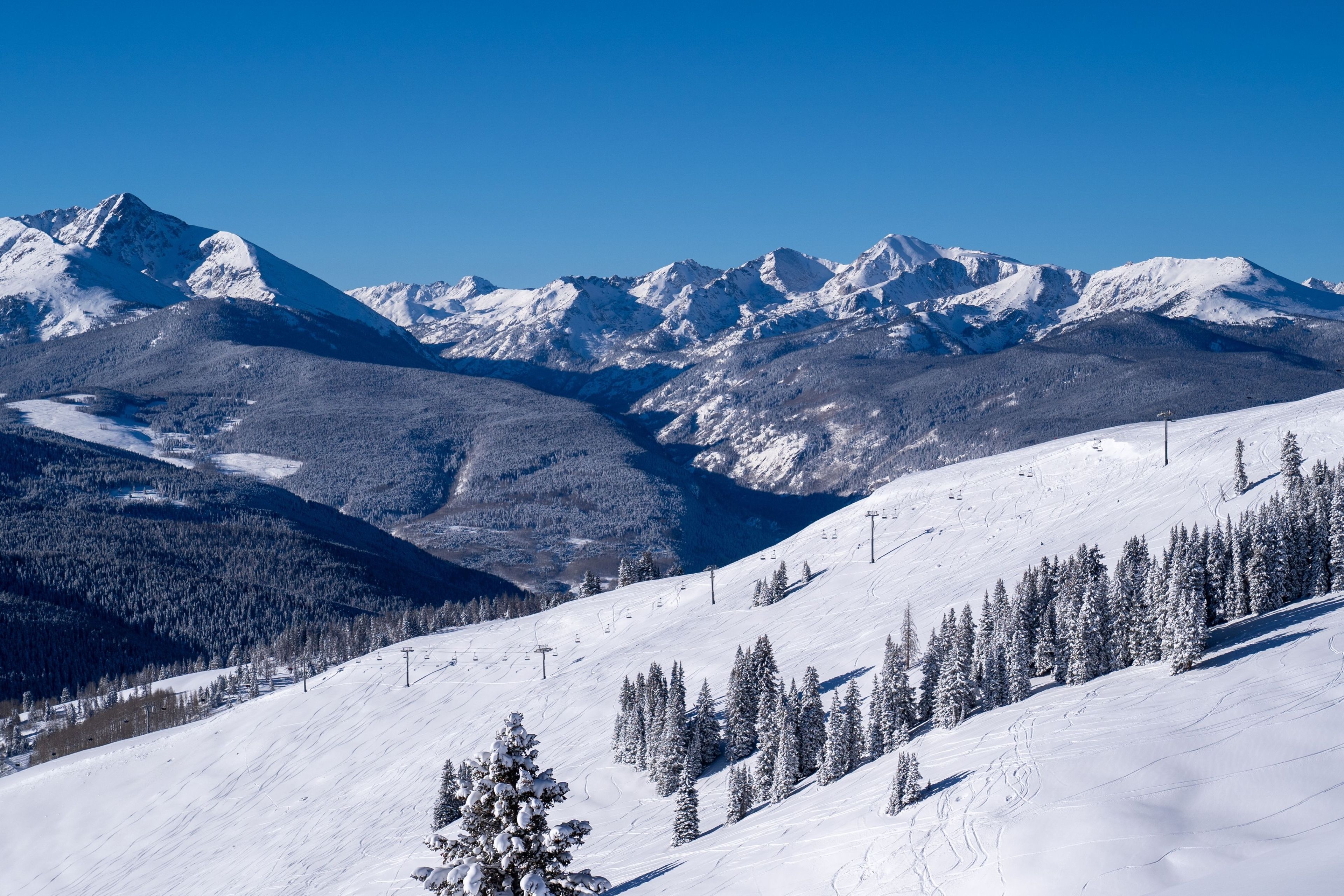 A snow-covered mountain landscape with ski slopes and a clear sky.