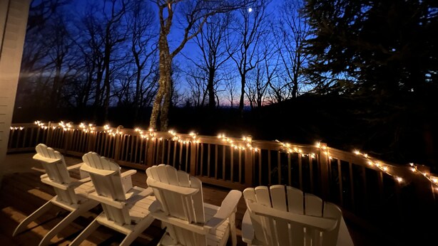 An outdoor seating area with Adirondack chairs and string lights. - Mountain home close to resort, trails, breweries, & more! (Wintergreen Resort)