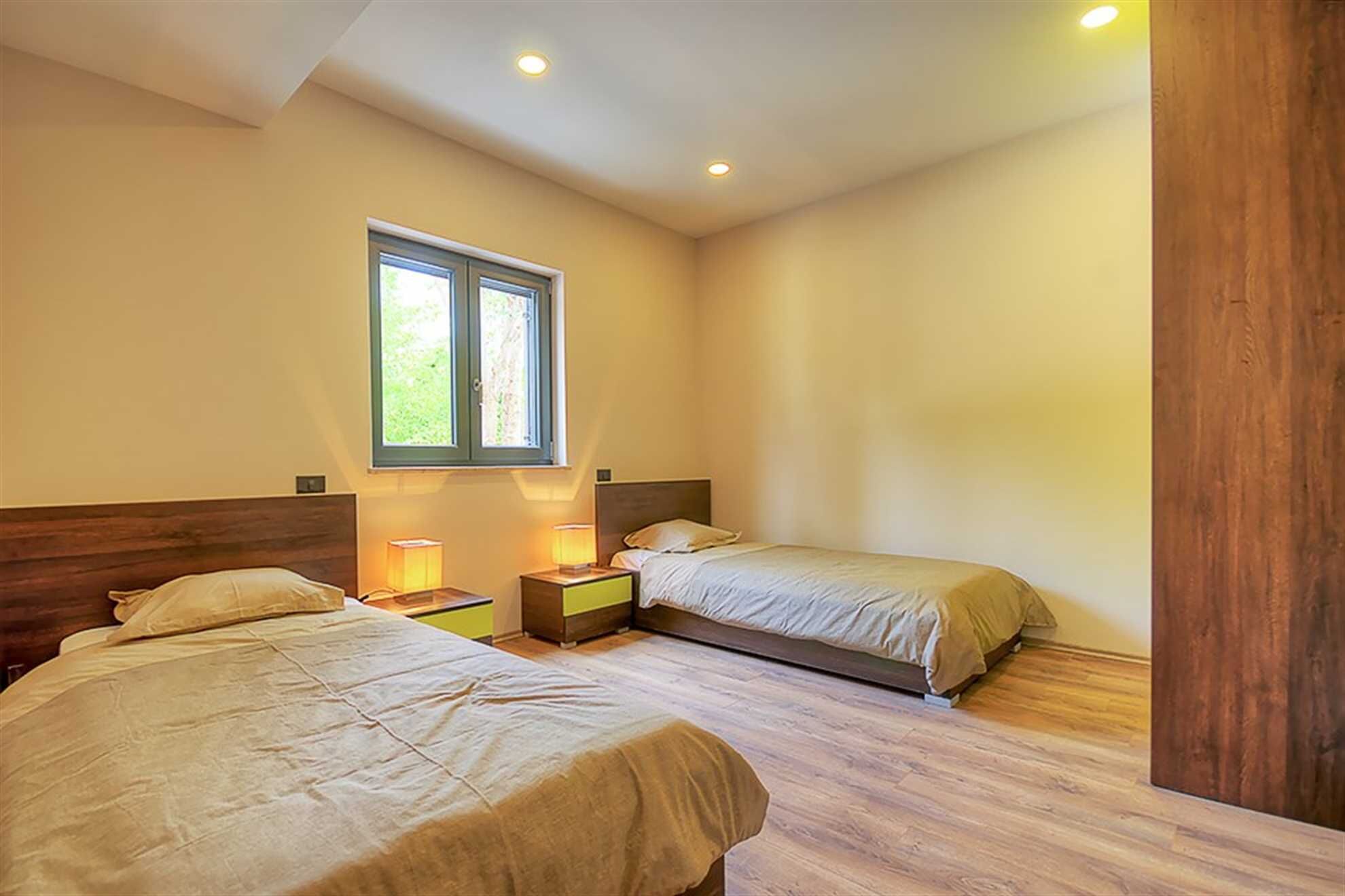 Une chambre avec deux lits, une fenêtre et des lampes de chevet.