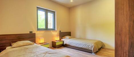 A bedroom with two beds, a window, and bedside lamps.