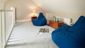 A room with a sloped ceiling, a white railing, a blue bean bag chair, a wooden dresser, and a lamp. - Two bedroom cottage situated in a quiet location down a secluded lane.  (Harome)