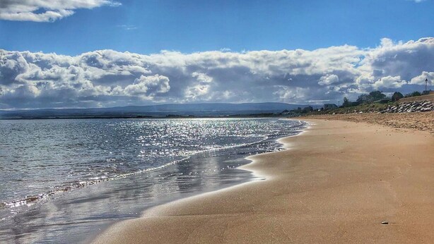 Une plage avec un ciel dégagé et une mer calme.