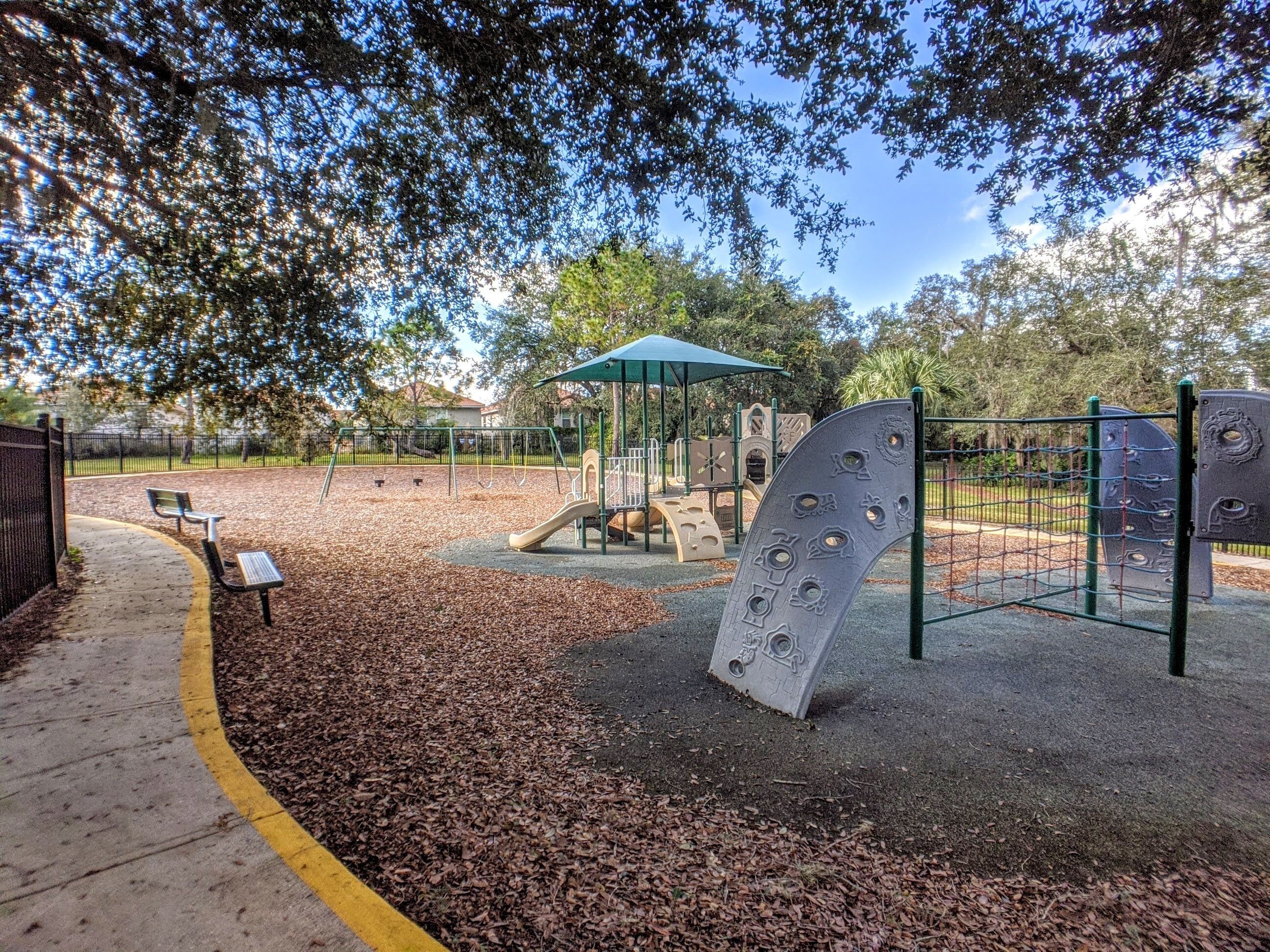 A playground with a slide, climbing structures, and a covered seating area.
