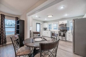 A modern kitchen with white cabinets, stainless steel appliances, and a dining area with a round table and chairs. - "Beulah Beauty"- High-Quality Renovation & Prime Location in Statesville (Statesville)