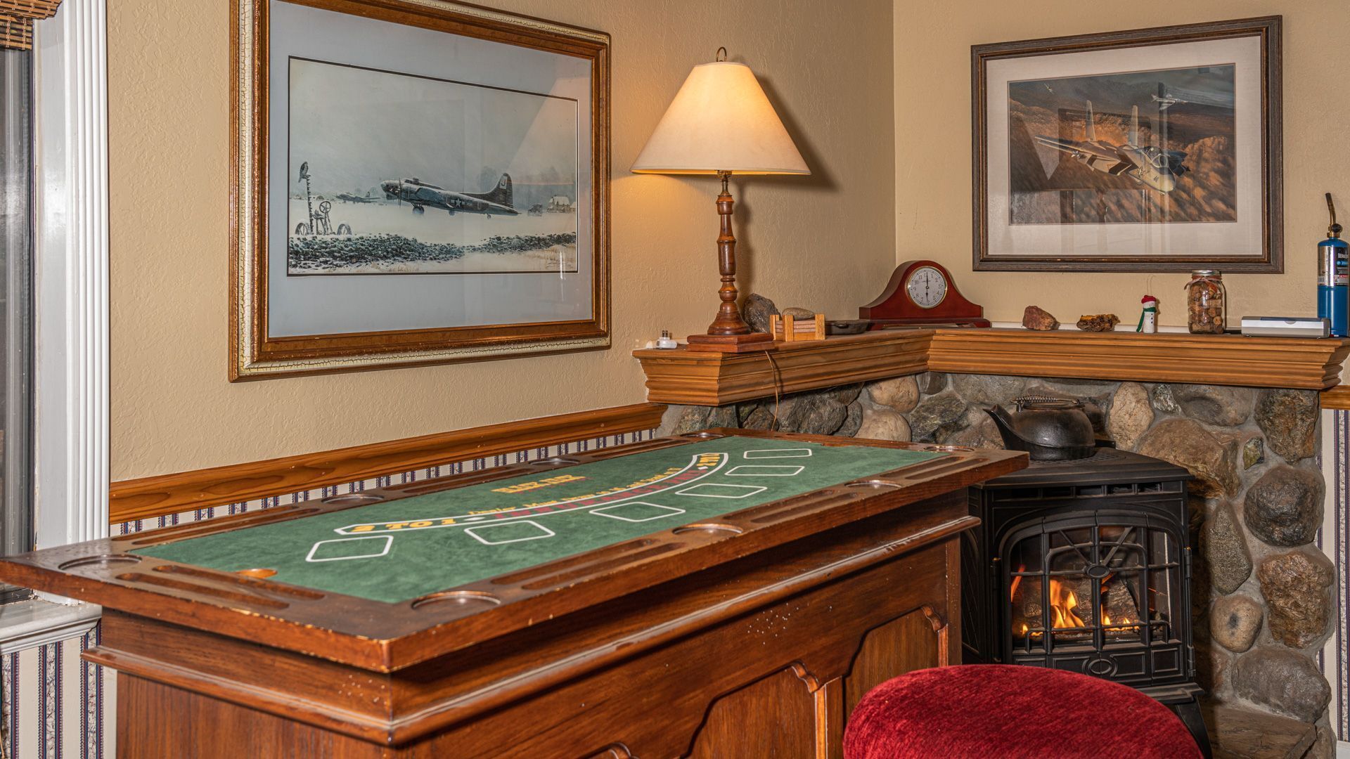 A room with a wooden pool table, a fireplace, and framed pictures on the walls.