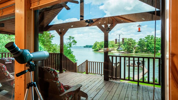 A wooden deck with a telescope, overlooking a lake with a dock and a lighthouse. - Serene Lakeside Getaway (Pittsburg)