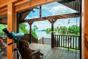 A telescope on a deck overlooking a lake with a wooden railing and a view of the water.