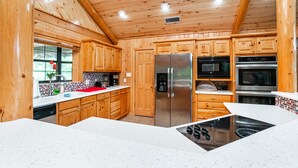 A modern kitchen with wooden cabinets, stainless steel appliances, and a white countertop. - Serene Lakeside Getaway (Pittsburg)