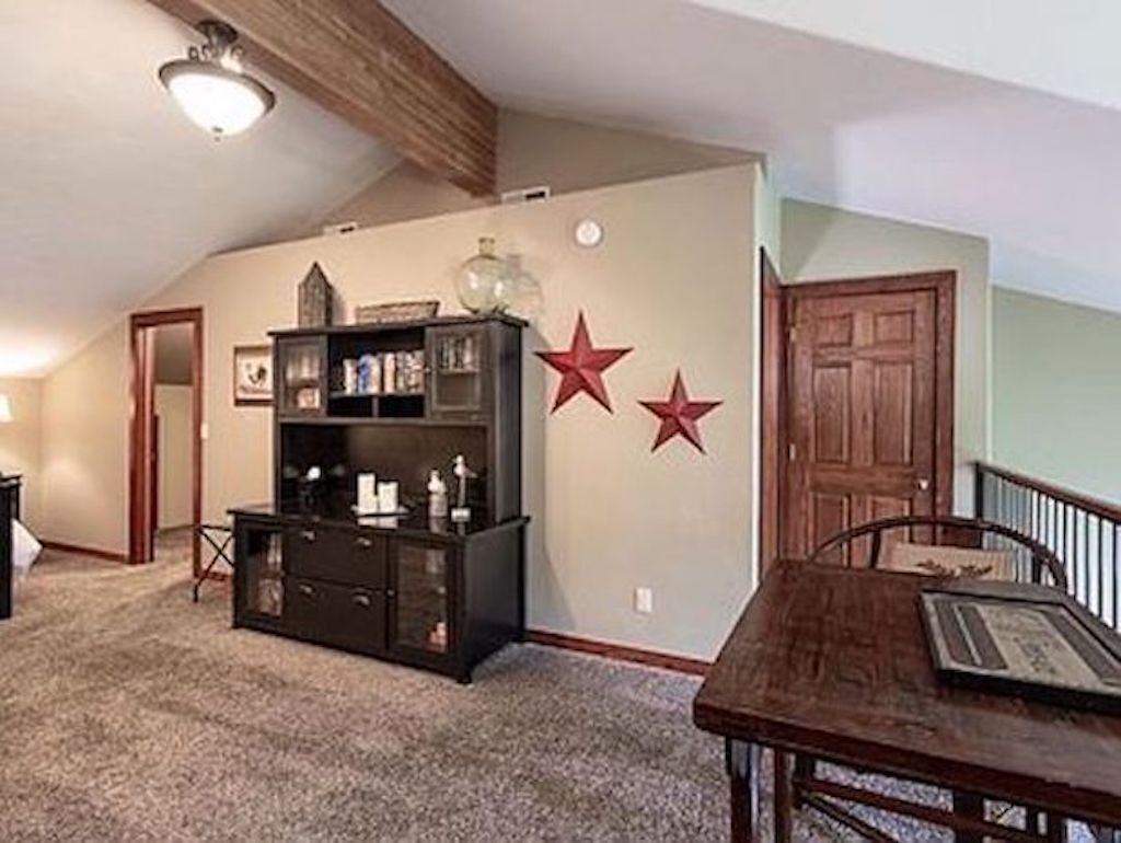 Una habitación con techo de madera, un mueble oscuro de madera, una mesa y dos estrellas rojas en la pared.
