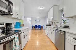 A modern kitchen with white cabinetry, a stainless steel range, and a coffee maker.