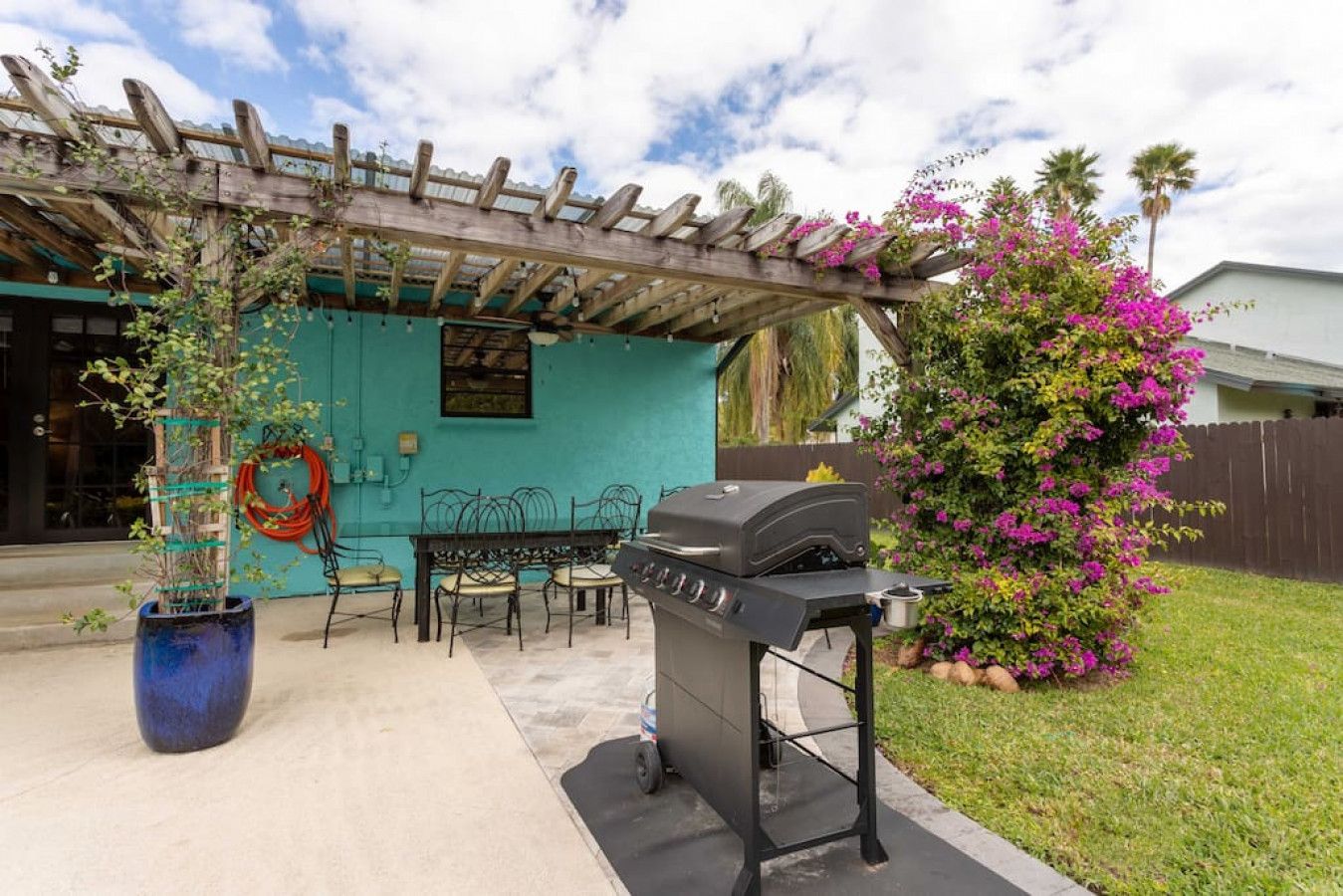 Eine Außenpatio mit Grill, Stühlen und einem Blumentopf.
