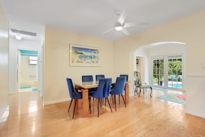 A dining area with a table and chairs, a ceiling fan, and a painting on the wall.