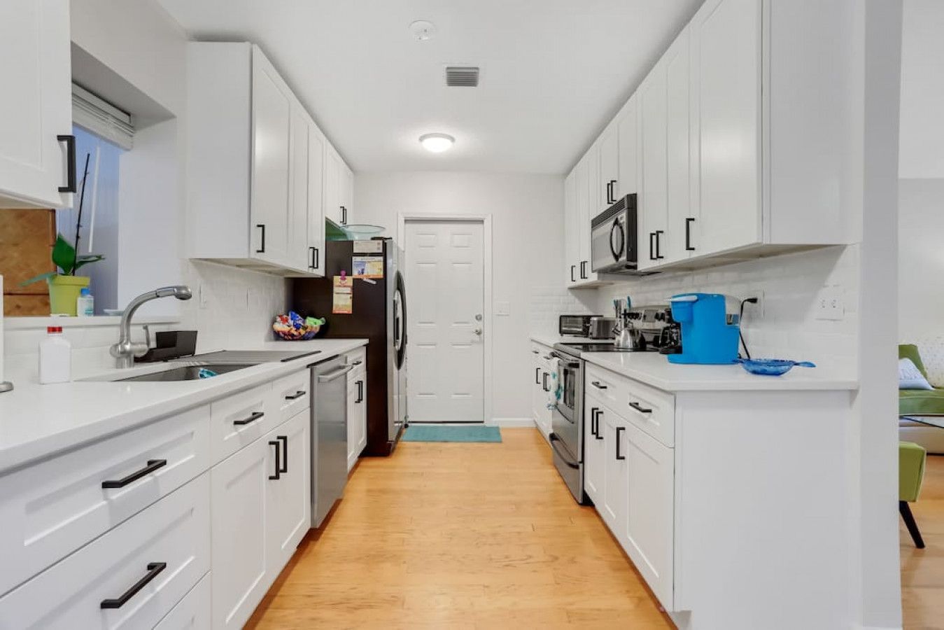 A modern kitchen with white cabinetry, a stainless steel sink, and a microwave.