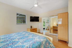 A bedroom with a bed, a TV, a wardrobe, and a window with blinds.