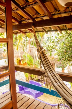 Une terrasse en bois avec un hamac, entourée d’une végétation tropicale luxuriante.