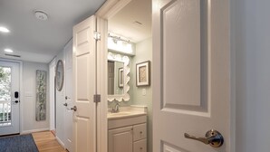 A hallway leading to a bathroom with a vanity, a mirror, and a door with a handle. - 3BR End Unit Spinnaker w/ Beach Boardwalk Access Across Street! Amenity access included! NO pets (Seabrook Island)