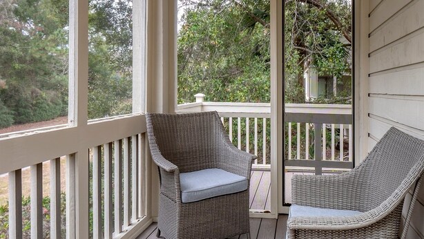 A covered porch with wicker furniture and a view of trees. - 3BR End Unit Spinnaker w/ Beach Boardwalk Access Across Street! Amenity access included! NO pets (Seabrook Island)