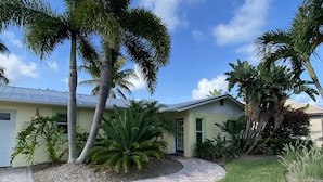 A residential property with a brick pathway, palm trees, and a well-maintained lawn. - A Tropical 2 Bedroom/2 Bath House w/ Pool and Dock (Osprey)
