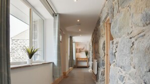 A hallway with stone walls, a wooden bench, and a potted plant by a window. - 3 bedroom accommodation in Penygroes, Caernarfon (Penygroes, Caernarfon)