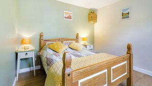 A neatly arranged bedroom with a wooden bed, two bedside tables with lamps, and two wall-mounted light fixtures. - 1 bedroom accommodation in Booton, Reepham (Booton, Reepham)