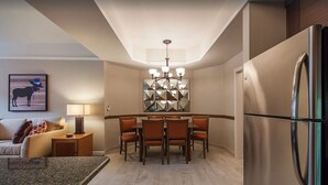 Une cuisine moderne avec un coin repas, un réfrigérateur, un lustre et un tableau au mur.