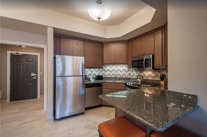 Enjoy cooking in this well-lit kitchen with a refrigerator, microwave, and granite countertop.