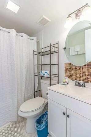 A bathroom with a toilet, a sink, a mirror, and a shower curtain.