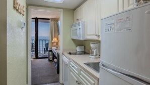 A kitchen with a microwave, toaster, coffee maker, and refrigerator. There is a view of the balcony and ocean through the door. - Sand Dunes 2626 (Myrtle Beach)