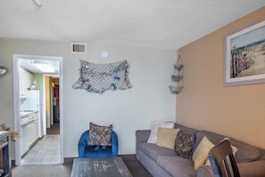 A living room with a grey sofa, a blue chair, and a wall-mounted artwork.