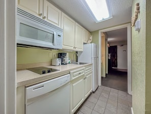 A compact kitchen with a microwave, toaster, sink, and dishwasher.