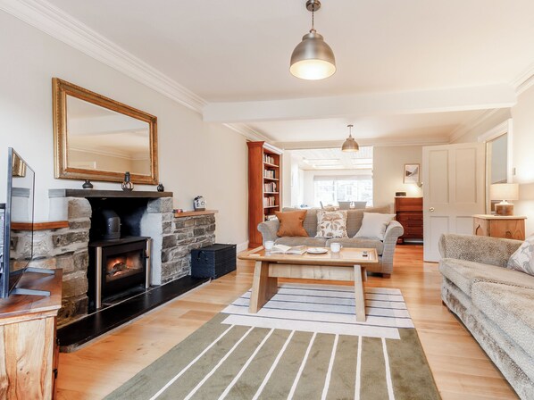 A living room with a fireplace, a sofa, a coffee table, and a bookshelf.