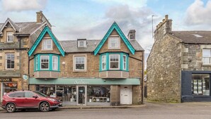 A traditional stone building with a shop on the ground floor and a car parked in front.