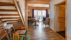A wooden interior with a staircase, a dining area, and a view to the outside.