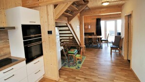 A spacious kitchen with modern appliances, a wooden staircase, and a dining area with a view.