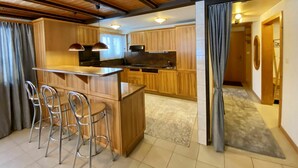Een moderne keuken met houten kastjes, een centraal eiland met barkrukken en hangende lampen.