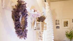 A wall with a hanging purple flower arrangement, a white vase with pink flowers, and a small wooden shelf with dried flowers. - Nice apartment for 6 guests with pool, WIFI, TV and patio (Zábreh)